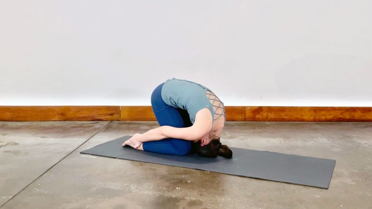 A person demonstrates Sasangasana (Rabbit Pose) in yoga