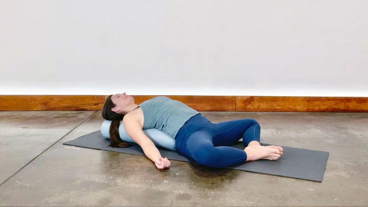 A person rests in Supta Baddha Konasana (Reclining Bound Angle Pose) in yoga