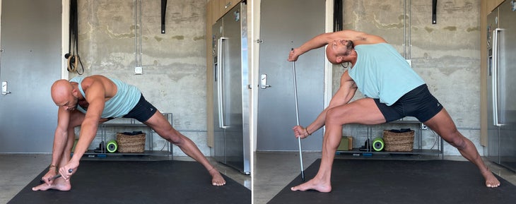 Parsvakonasana with a dowel. Yoga teacher Rocky Heron wears a light blue tank and dark shorts. He is standing on a dark/black mat with a concrete wall in the background.