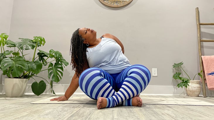 A person demonstrates Sukhasana with a half bind in yoga