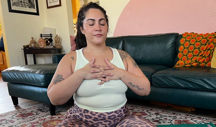 A person sits in Easy Seat with her hands on her chest