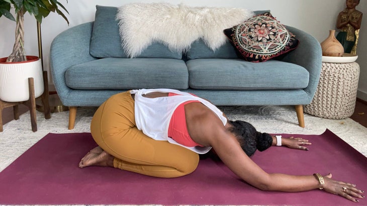 A person demonstrates Child's Pose (Balasana) in yoga