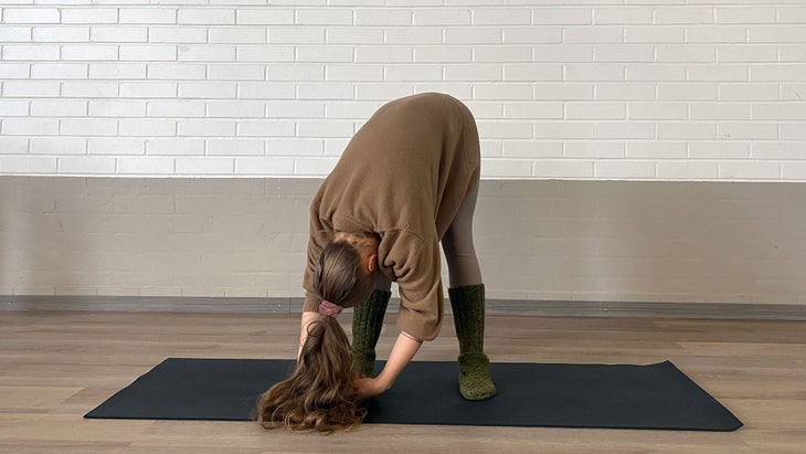 A person hangs forward at the hips in a rag doll pose in Yin Yoga