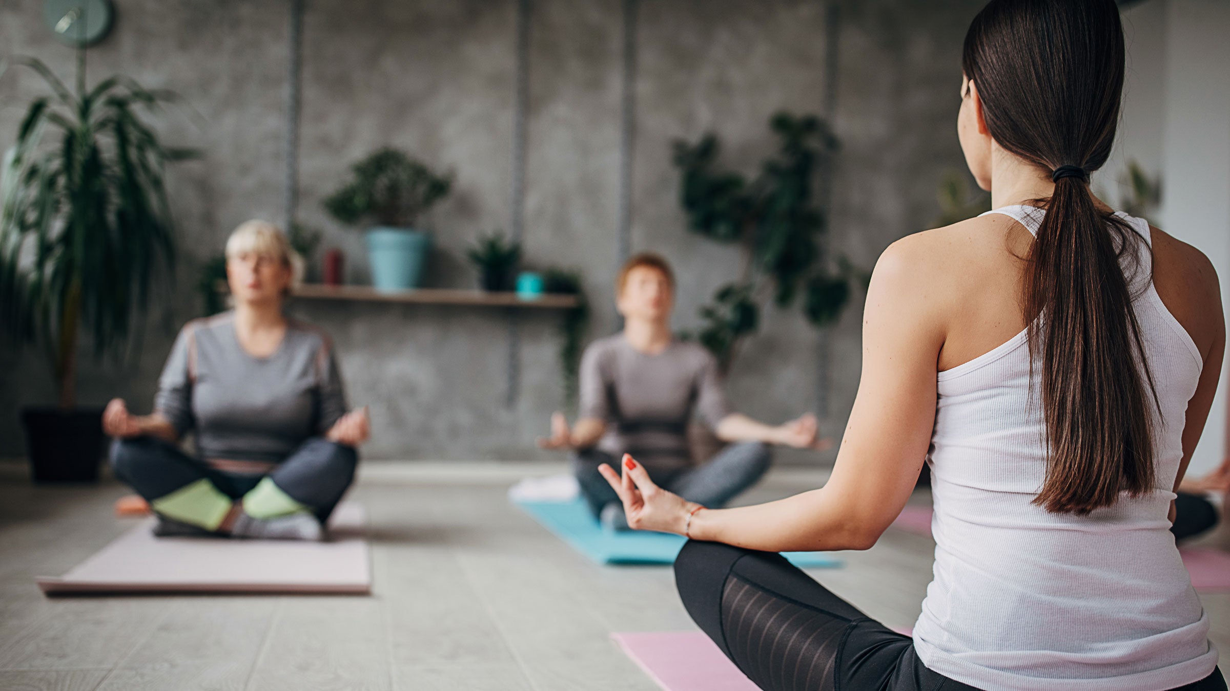 Woman teachers a yoga class to two students