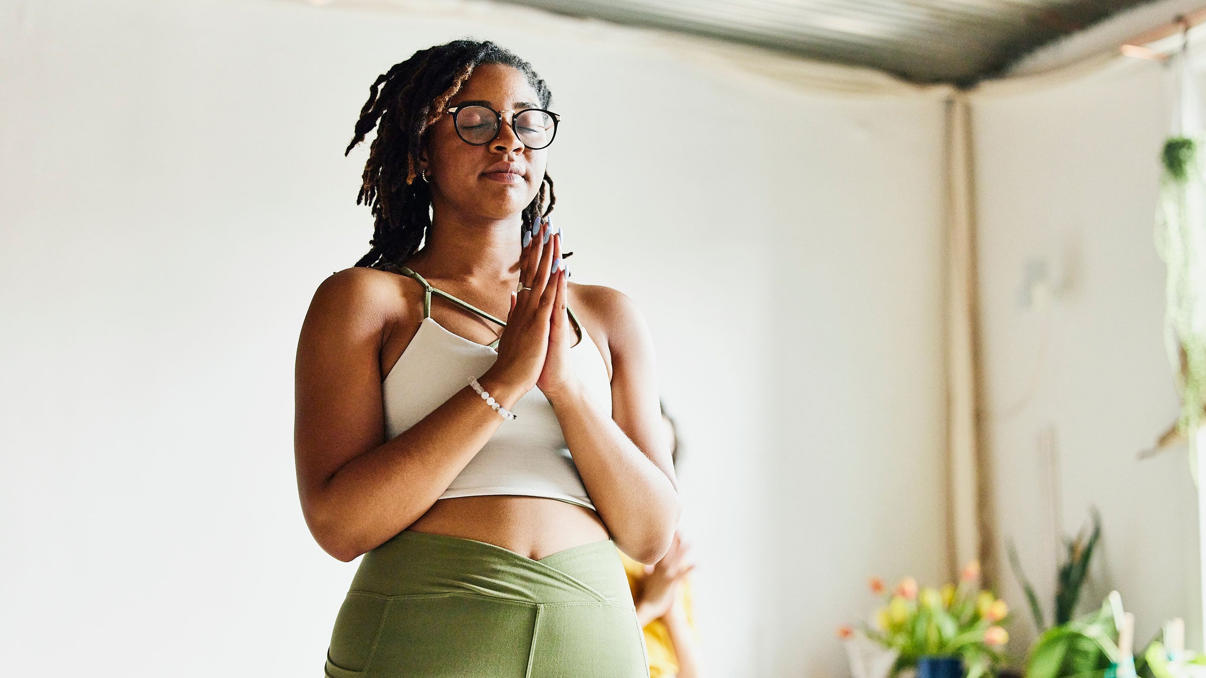 Woman practices a mindfulness exercise while standing up, hands close to her heart
