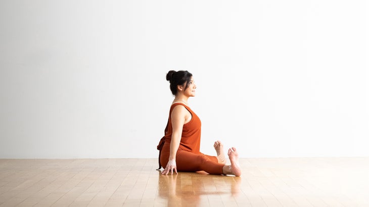 A woman with dark hair practices Upavistha Konasana
