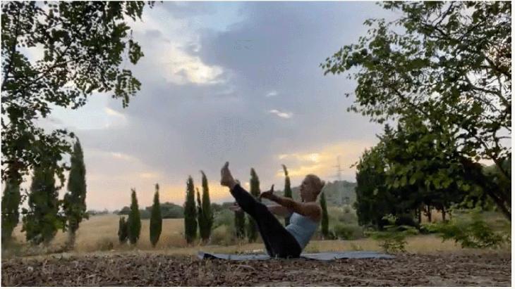 Woman practicing early morning yoga outside at sunrise in boat pose