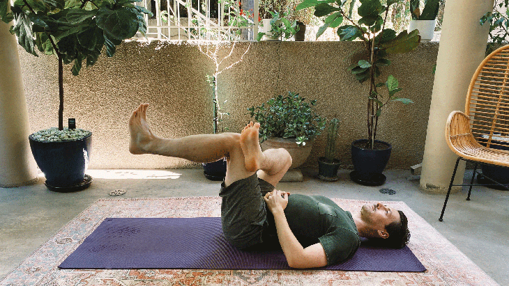 Man lying on his back on his yoga mat with his right ankle to his left thigh in a stretch for the hips