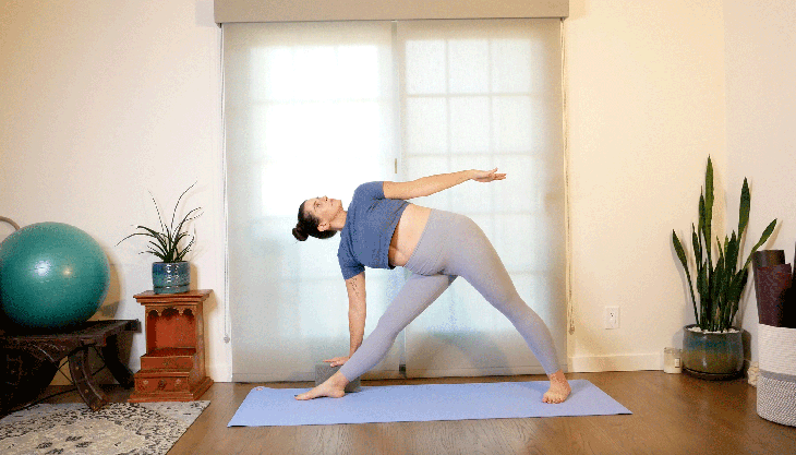 Woman with a shoulder injury on her yoga mat practicing a modification for her top arm in Triangle Pose