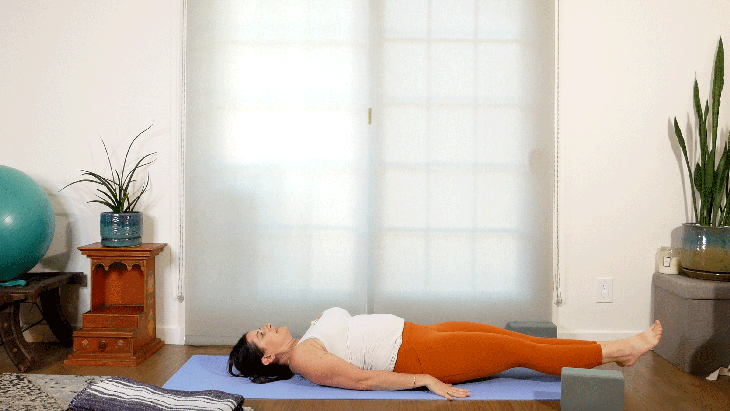 Woman lying on her yoga mat with her legs straight in front of her hovering above the mat for core work