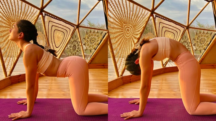 Woman with dark braid practices Marjaryasana/Bitilasana (Cat/Cow Pose) in a YogaDome, a geodesic dome in Patagonia. She is wearing peach colored tights and a light colored sports bra, and practices on a magenta colored mat. The room has wood floors and you can see crocheted covers on the triangular shaped windows. A view of the sky can be seen through the windows.