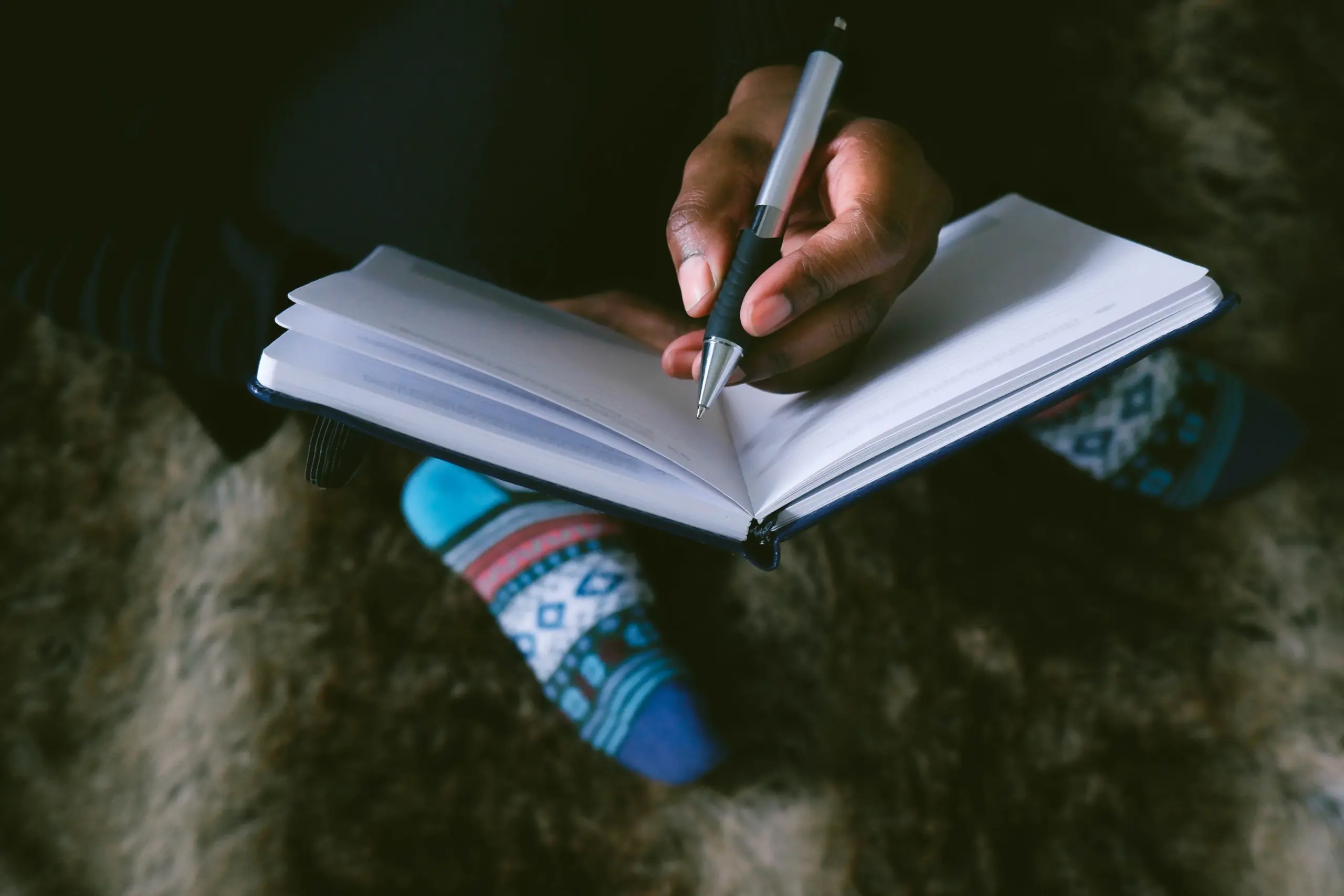 Woman's hands holding a pen and journal.