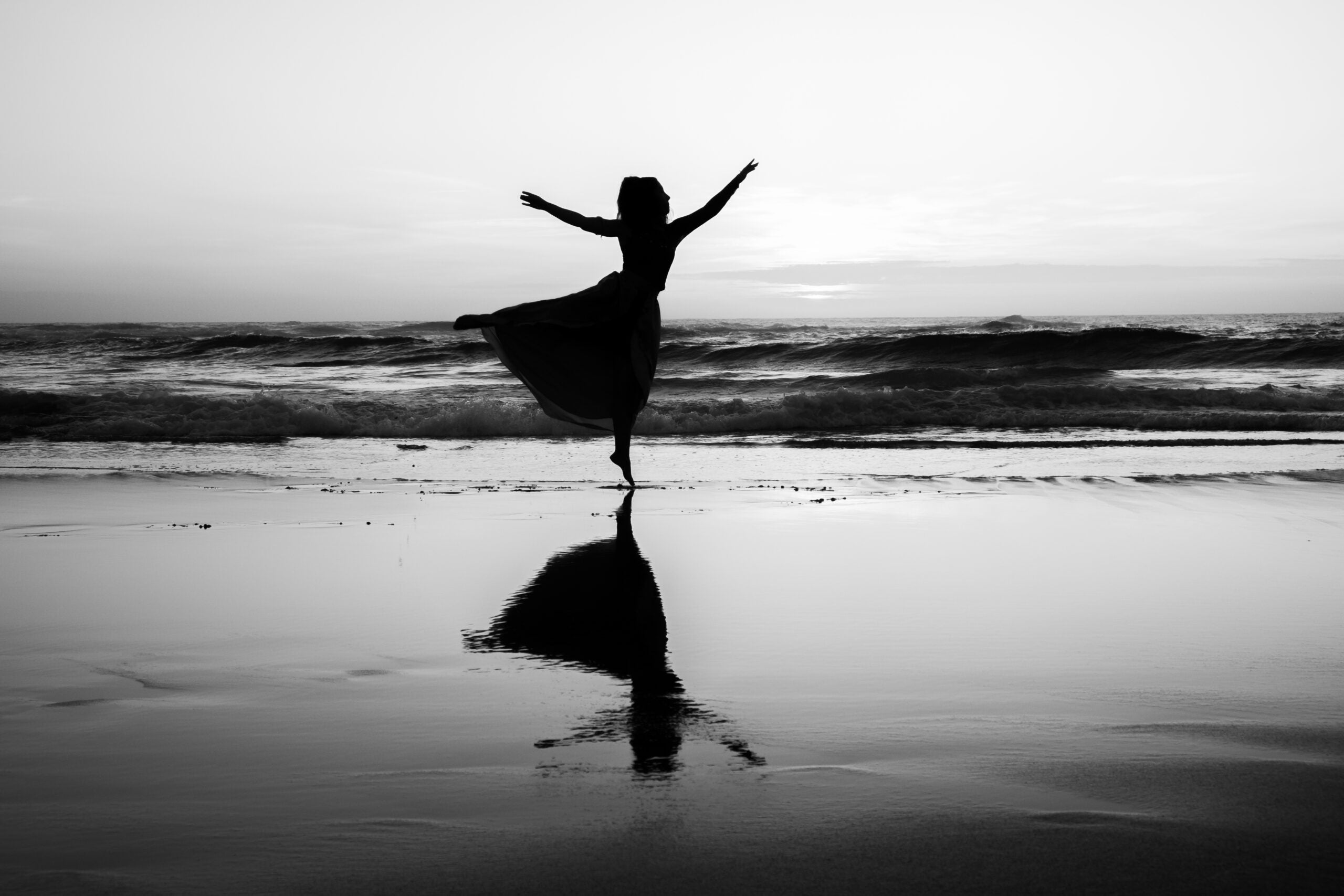 Woman dancing on the beach anticipating the astrology forecast for the week ahead