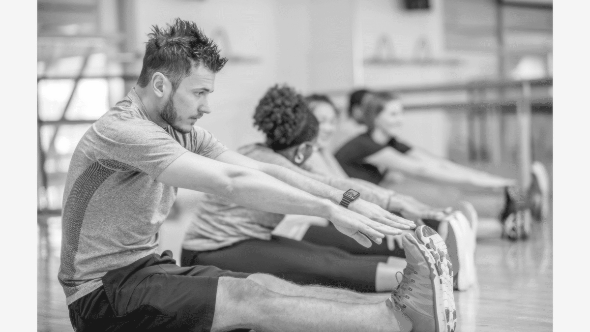 A man in a gym leaning forward but thinking I can't touch my toes