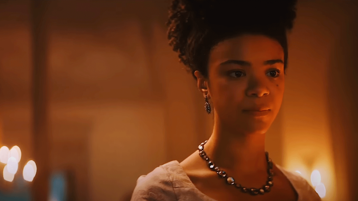 Queen Charlotte of A Bridgerton Story standing in her bedroom with King George III surrounded by candles