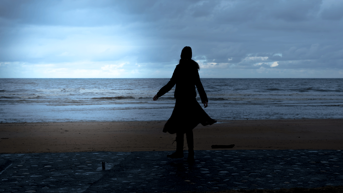 Woman dancing on a beach at night beneath the full Moon in Sagittarius