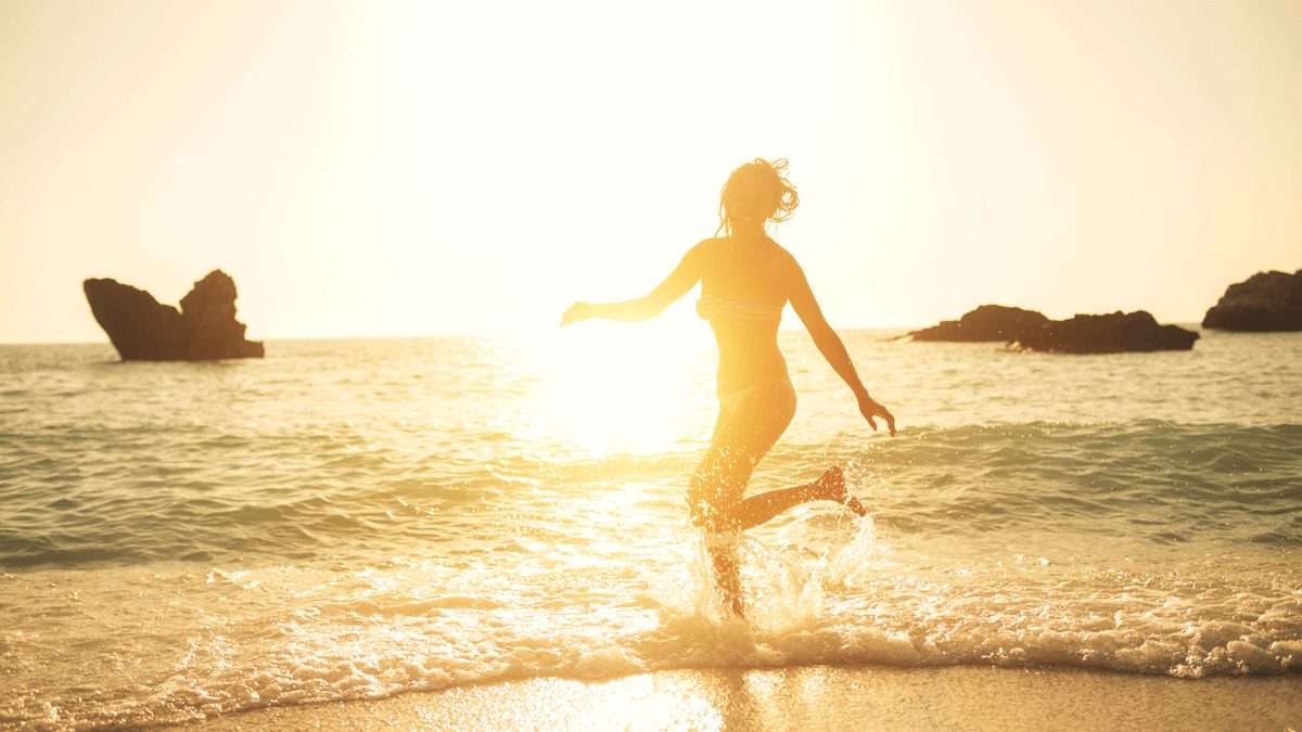 Woman dancing in the surf before sundown while laughing