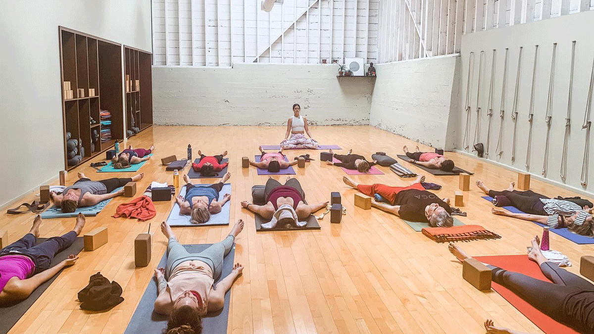 Yoga teacher Sarah Ezrin teaches a large studio filled with students