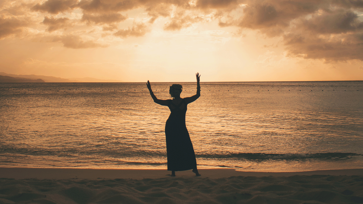 Woman standing on the beach at sunset considering the role of Leo in her weekly astrology forecast