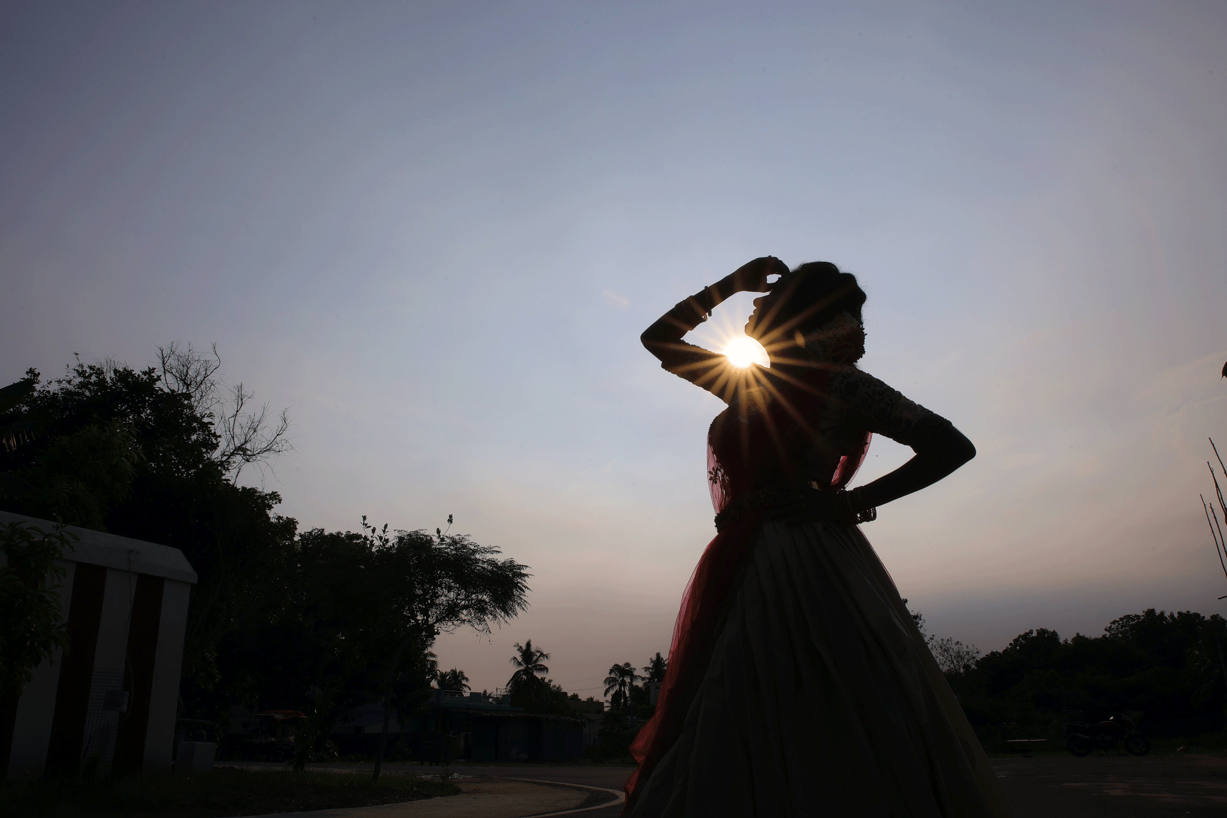 Silhouette of a woman standing outside at sunset with her hand to her head looking into the distance contemplating the weekly horoscope.
