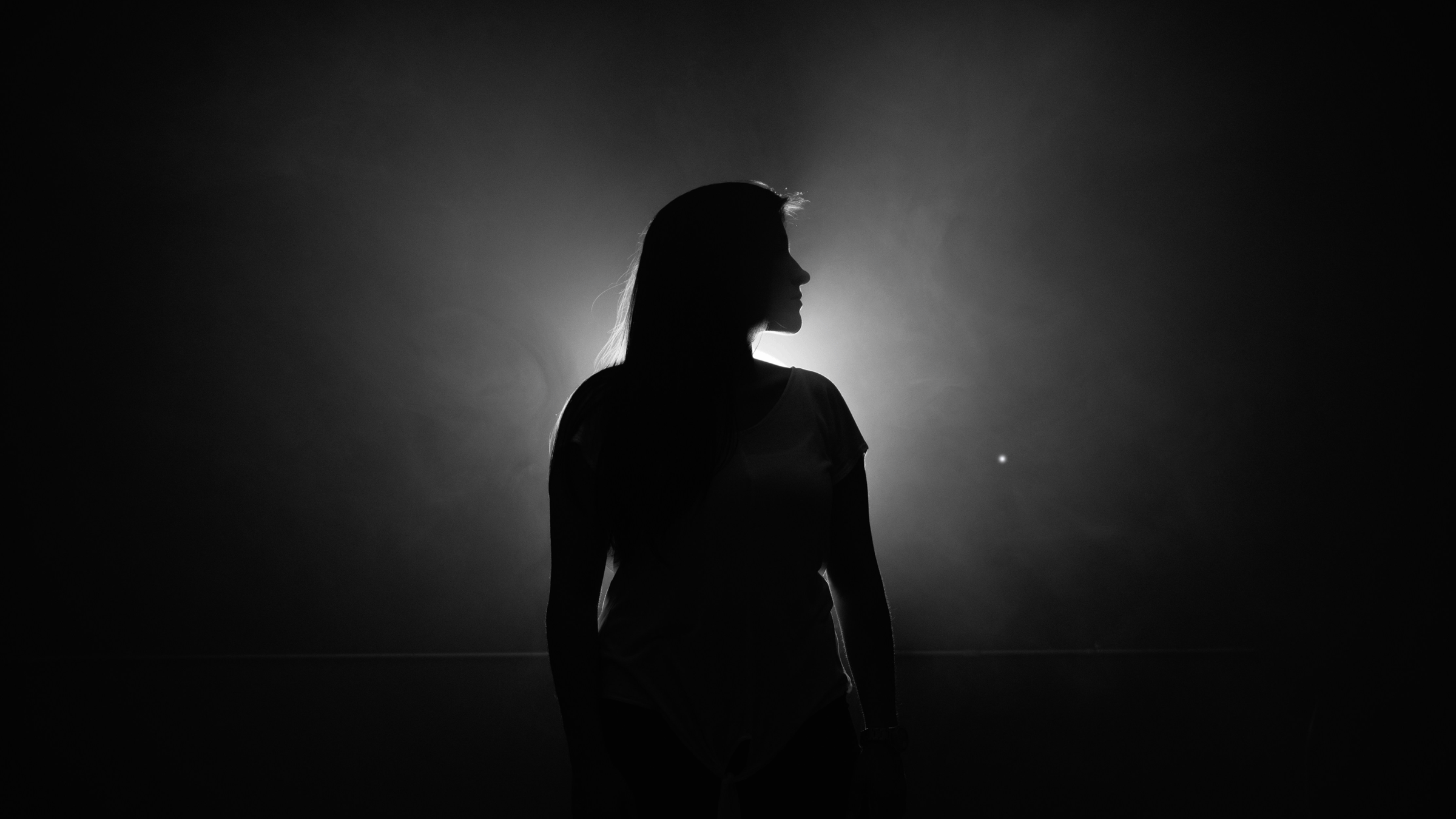 Woman standing outside at night in front of a full Moon and you can see her silhouette.