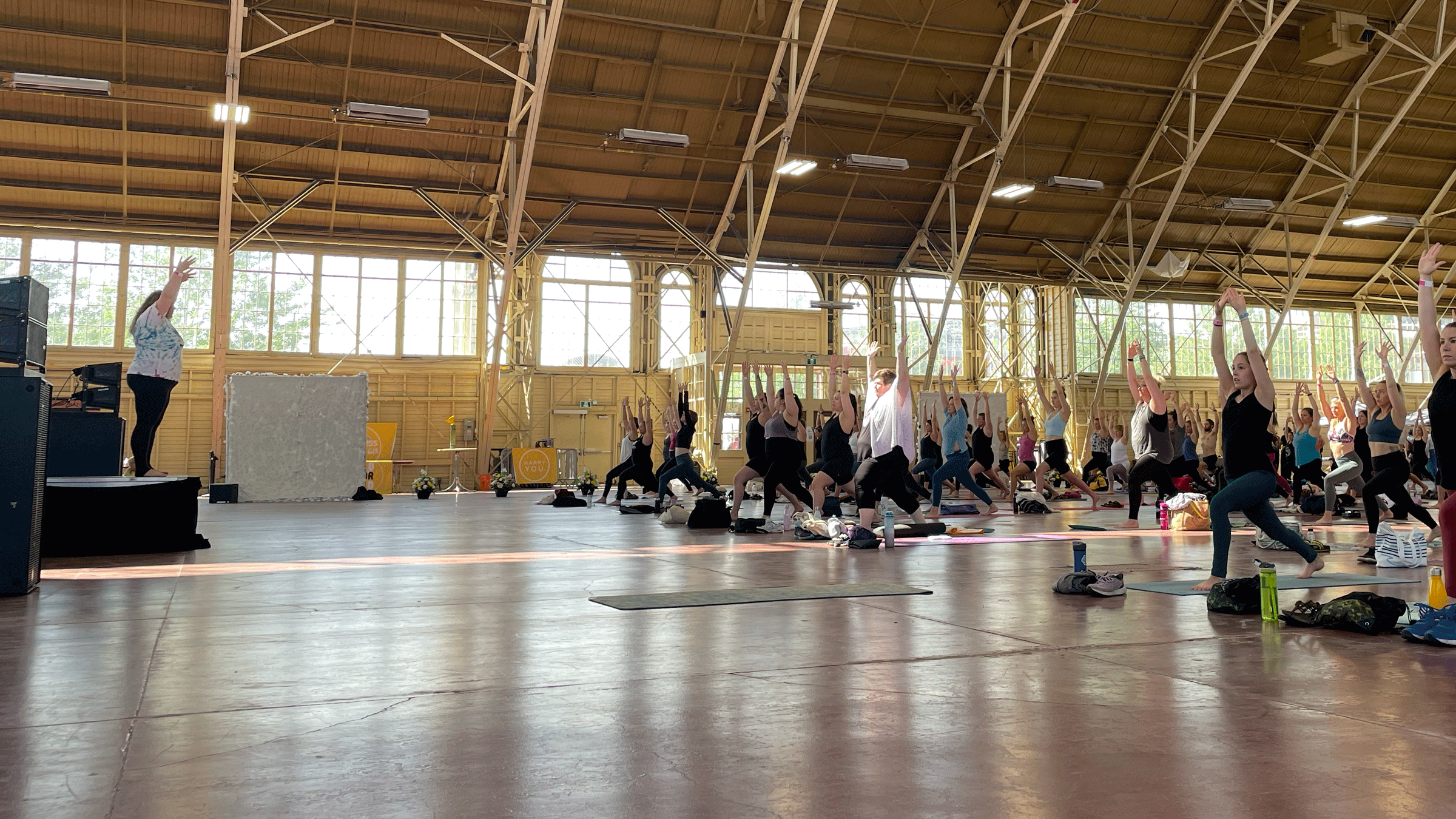 Yoga teacher Ellie Sheppard teaching in a gymnasium in front of dozens of students.