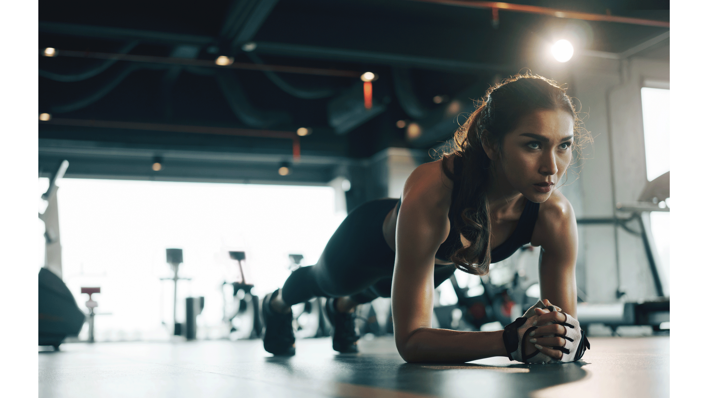Woman weight lifter practicing forearm plank during a core workout