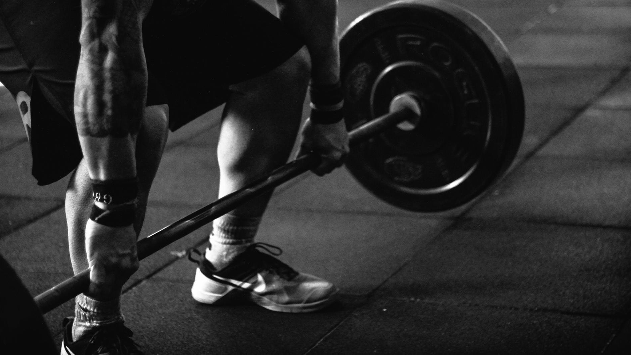Man with tattoos in a gym lifting a barbell