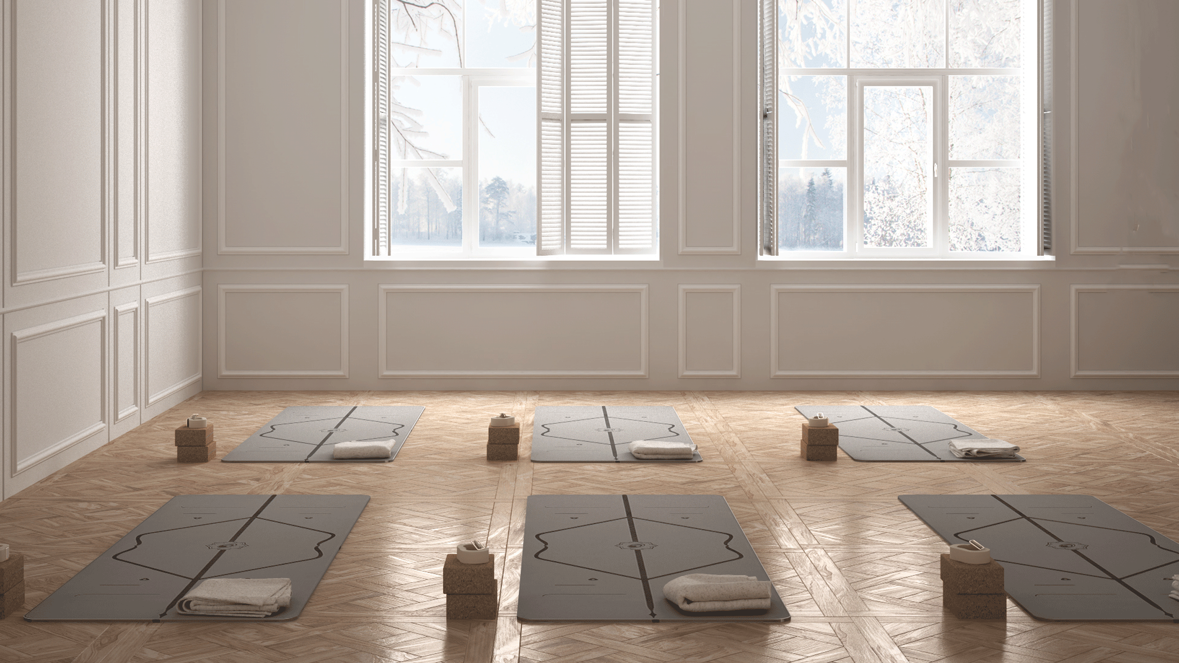 A yoga studio with hardwood floors, black mats, cork blocks, and white walls and two vintage windows