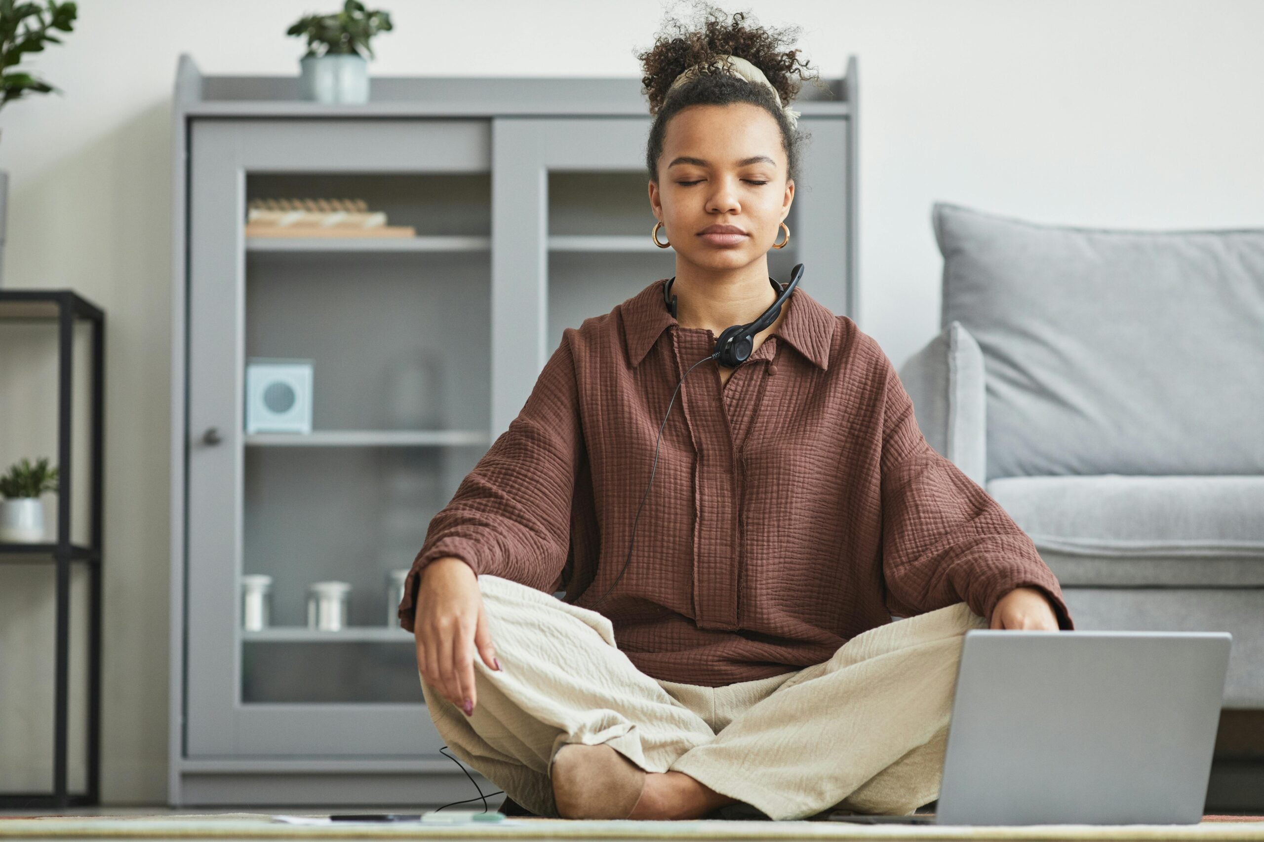 Young woman sitting cross-legged and listening to a guided meditation.