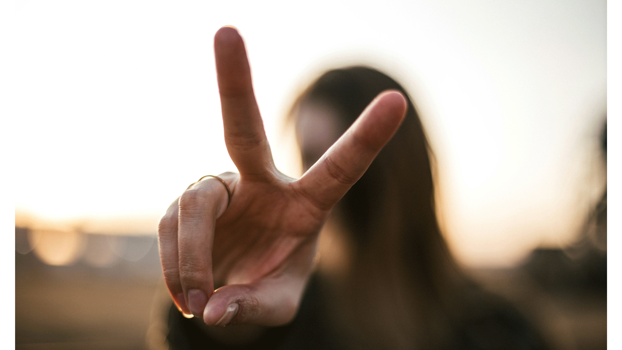 Woman outside holding up two fingers in a peace sign