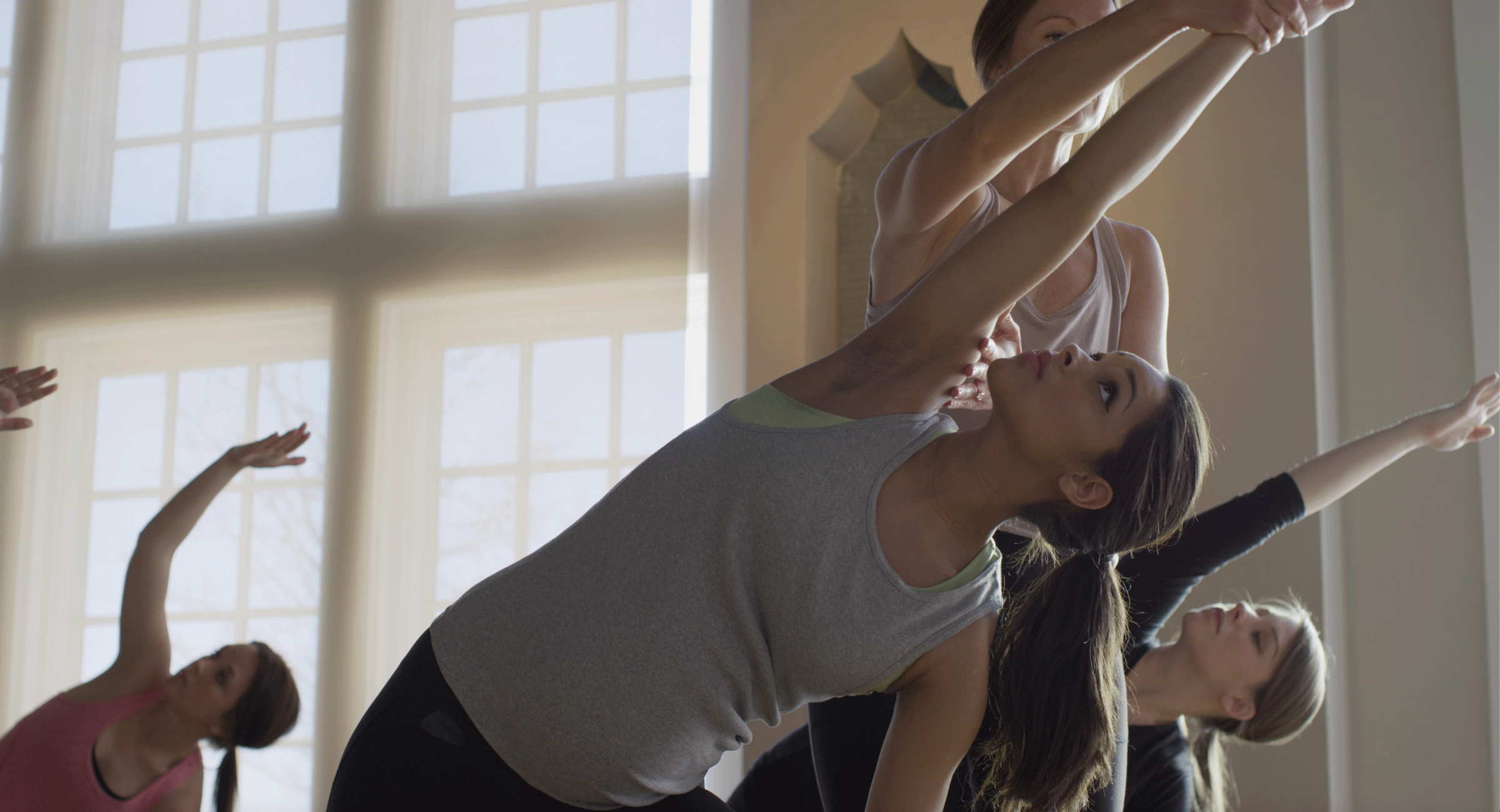 Yoga class with a student receiving a hands-on physical adjustment from a yoga teacher