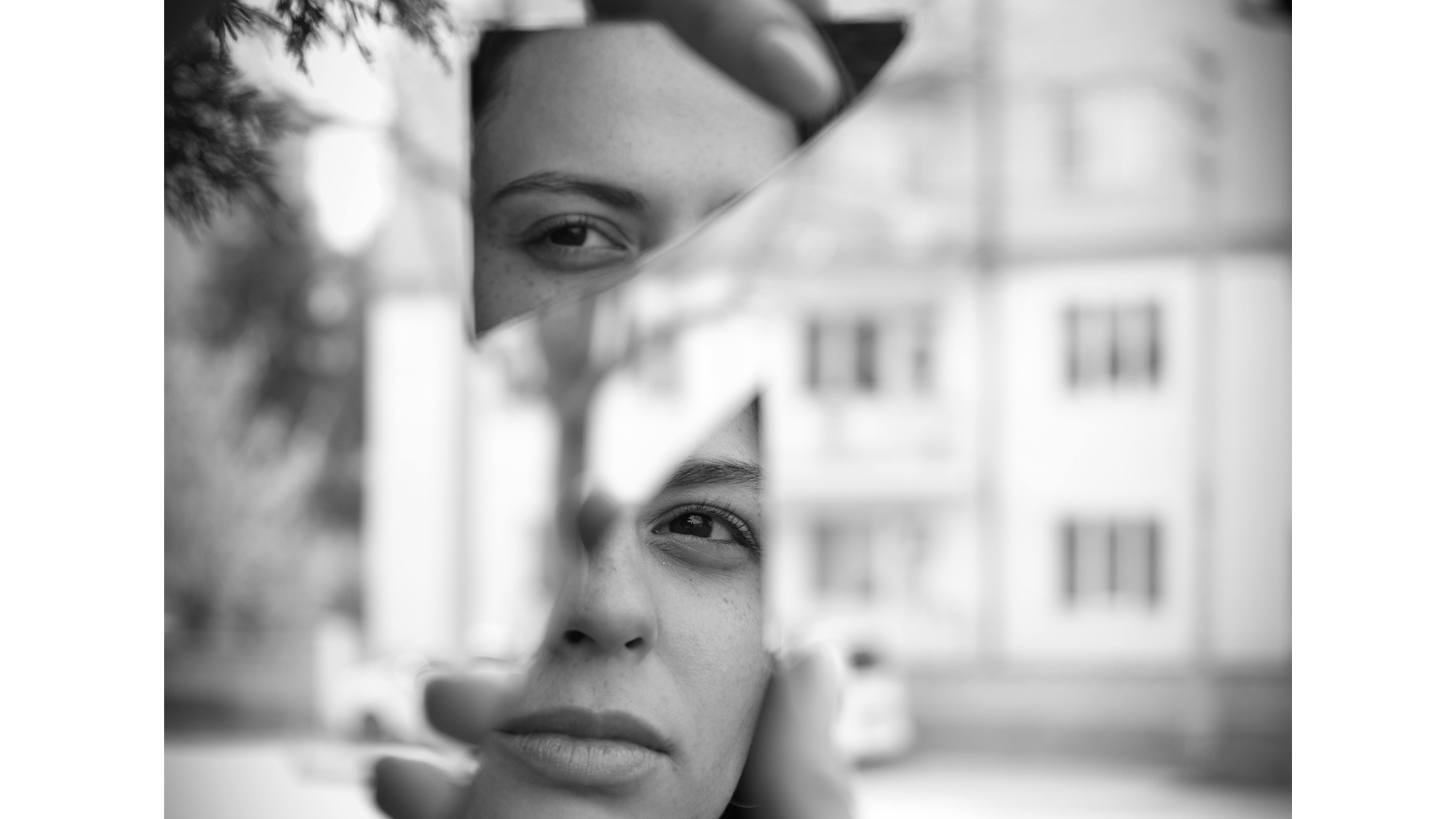 Black and white image of a woman looking at herself in a cracked mirror during Mars retrograde 2024