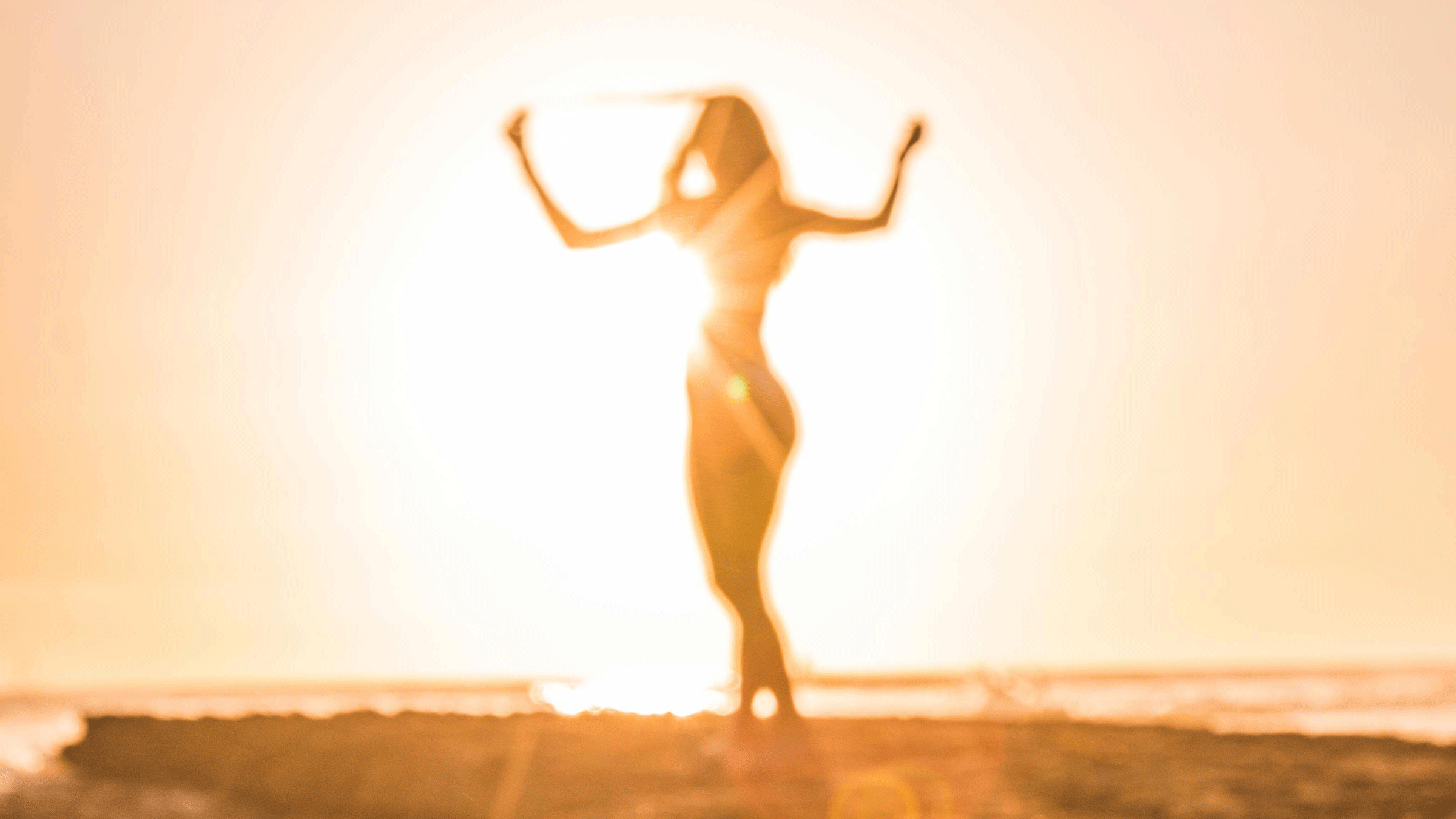 Silhouette of a woman in front of the sun on a beach contemplating her weekly horoscope for December 29, 2024, to January 4, 2025.