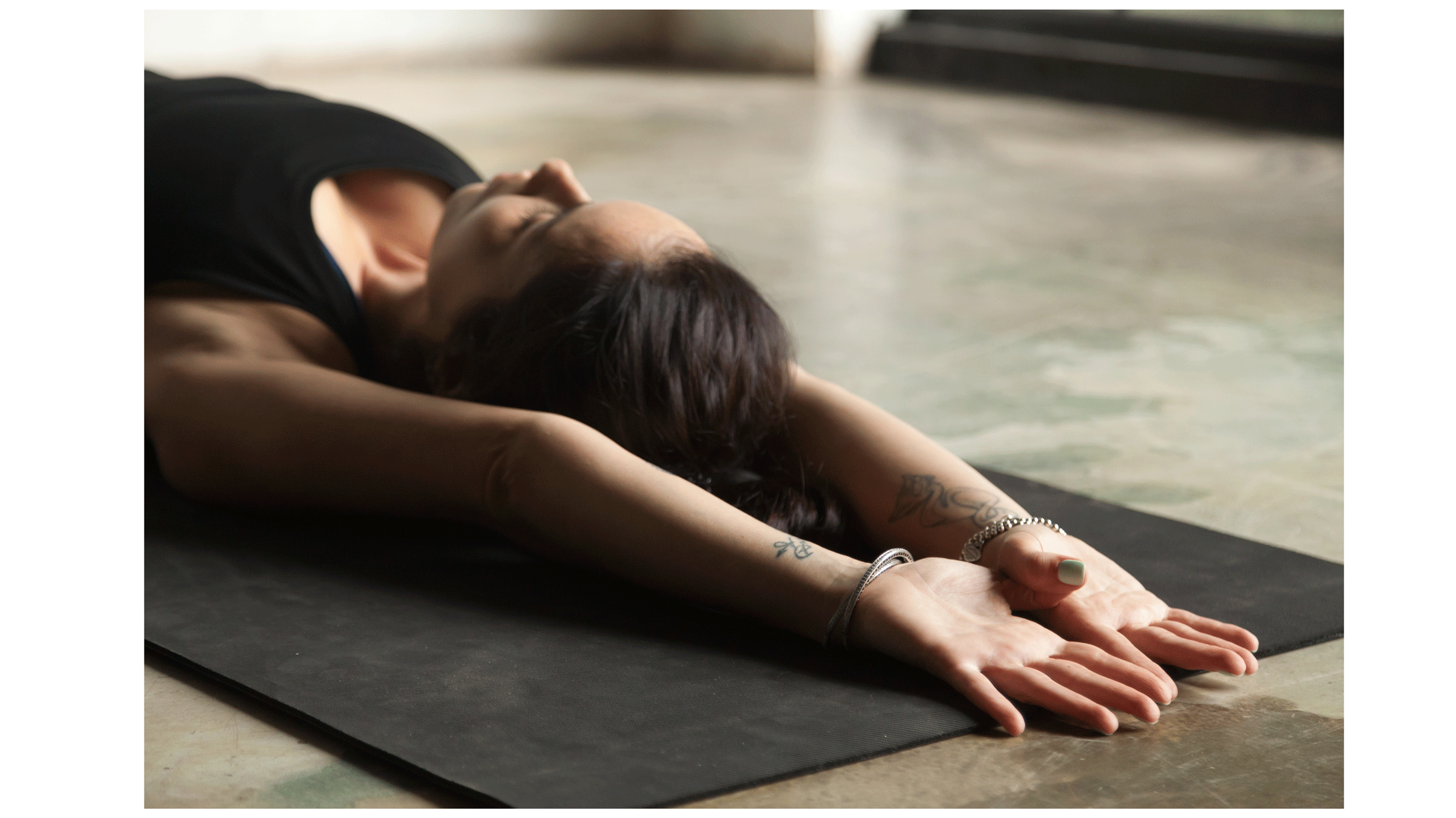 woman lying on a yoga mat while stretching