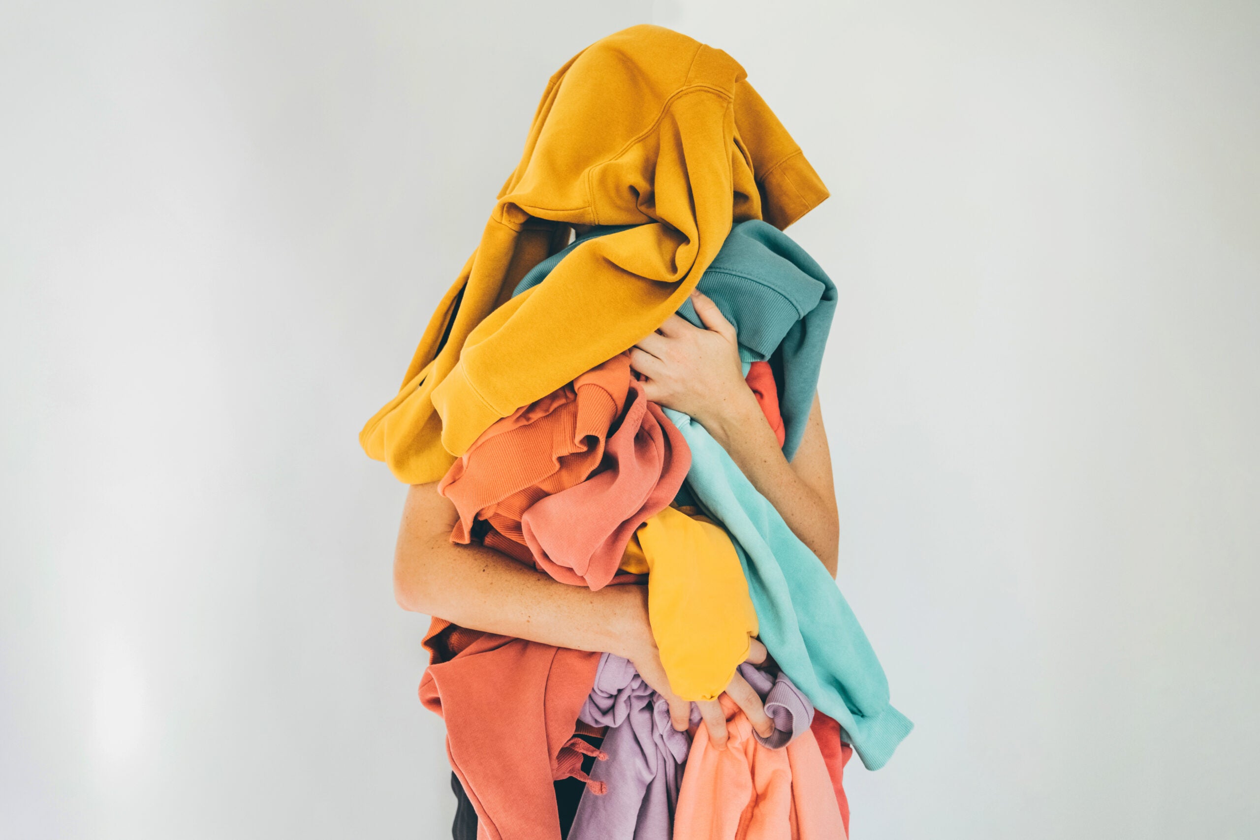 Image of person covered by multi-colored sweatshirts.