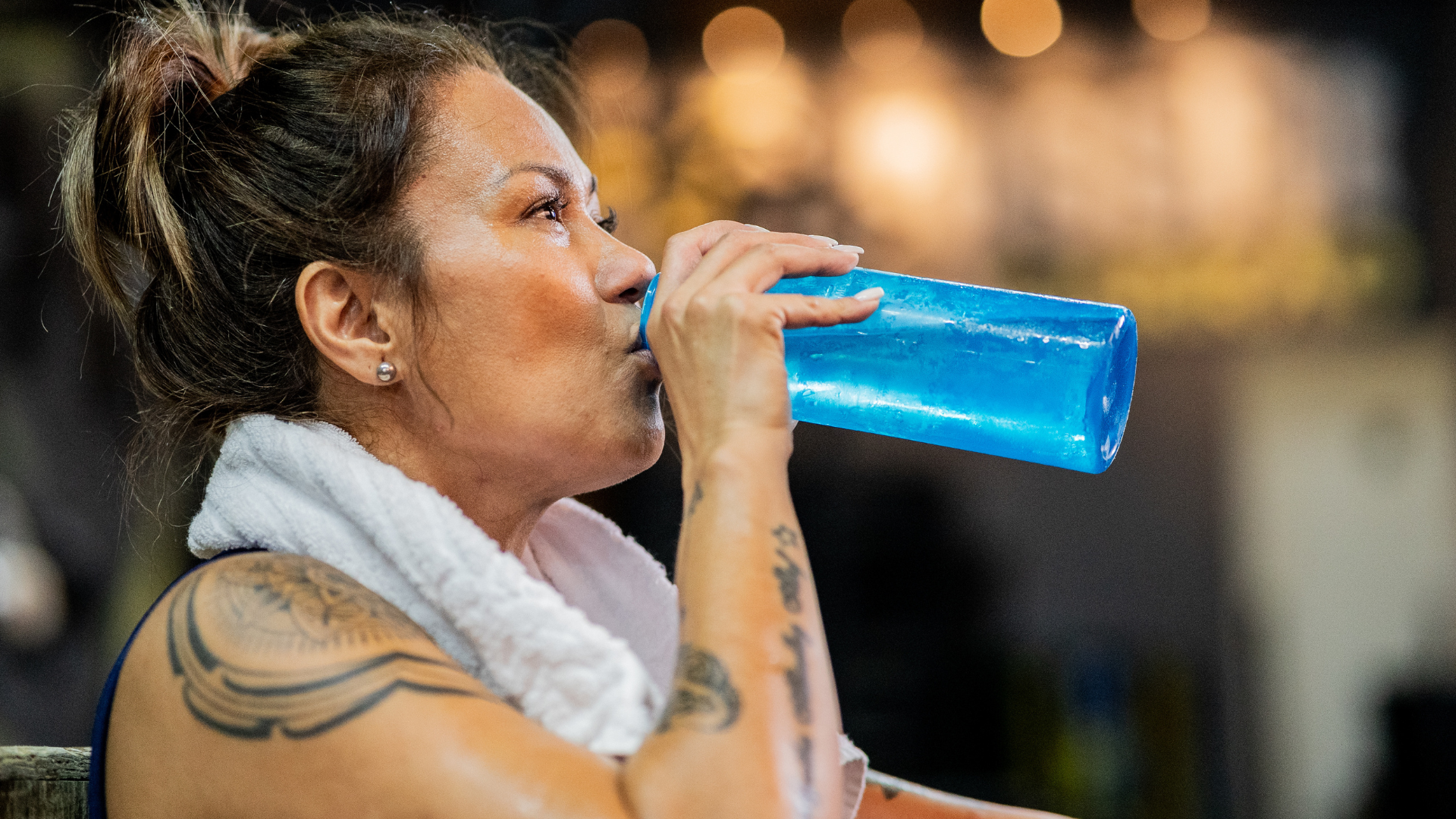 Woman staying hydrated during a hot yoga class by sipping water