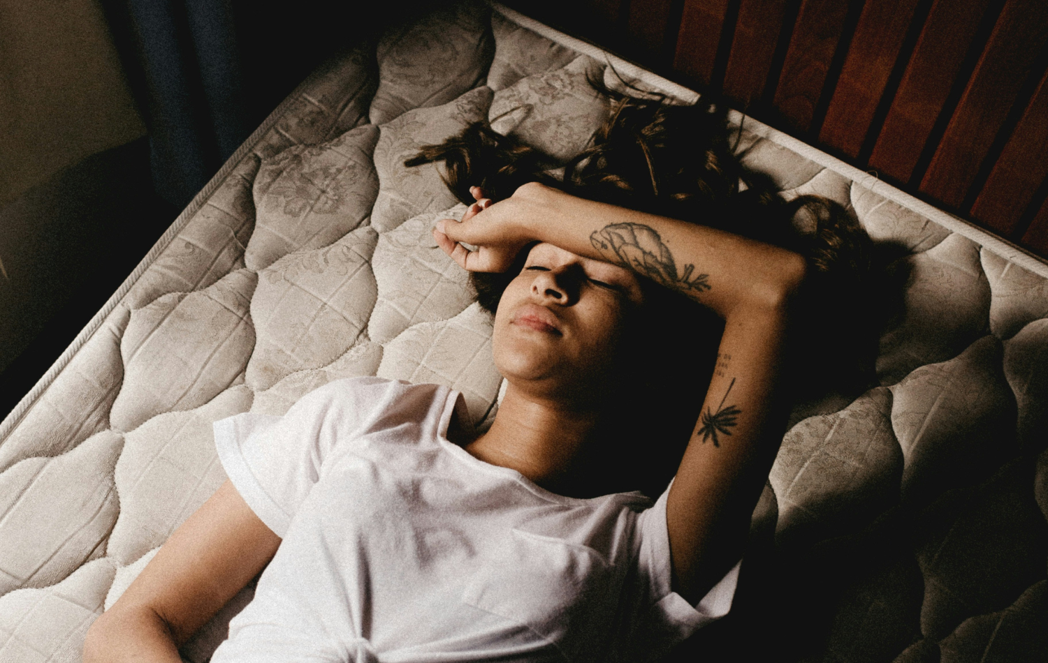 Woman lying on a mattress trying to understand how to fall asleep fast
