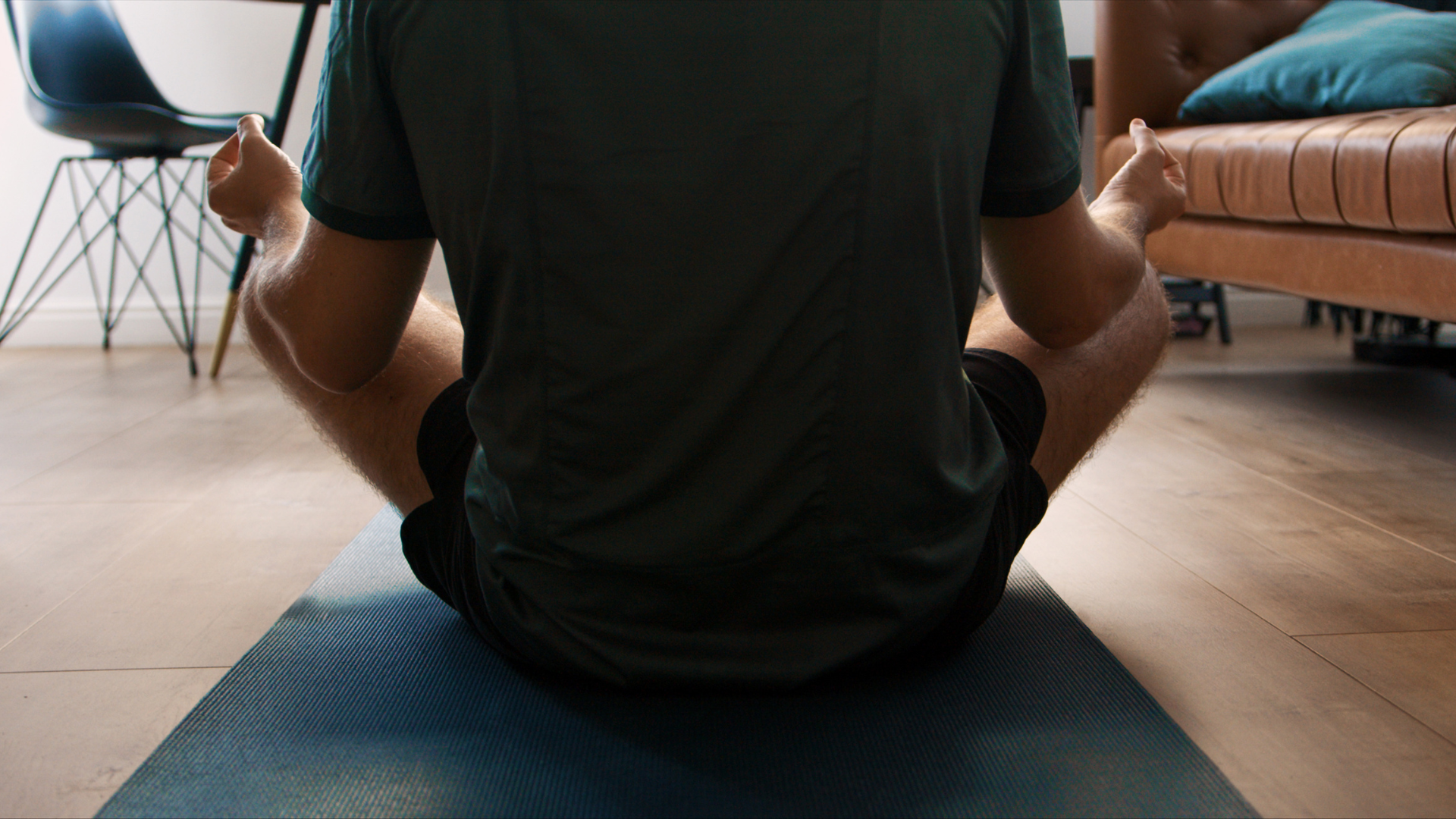 Yoga teacher sitting in meditation with a chair in the background