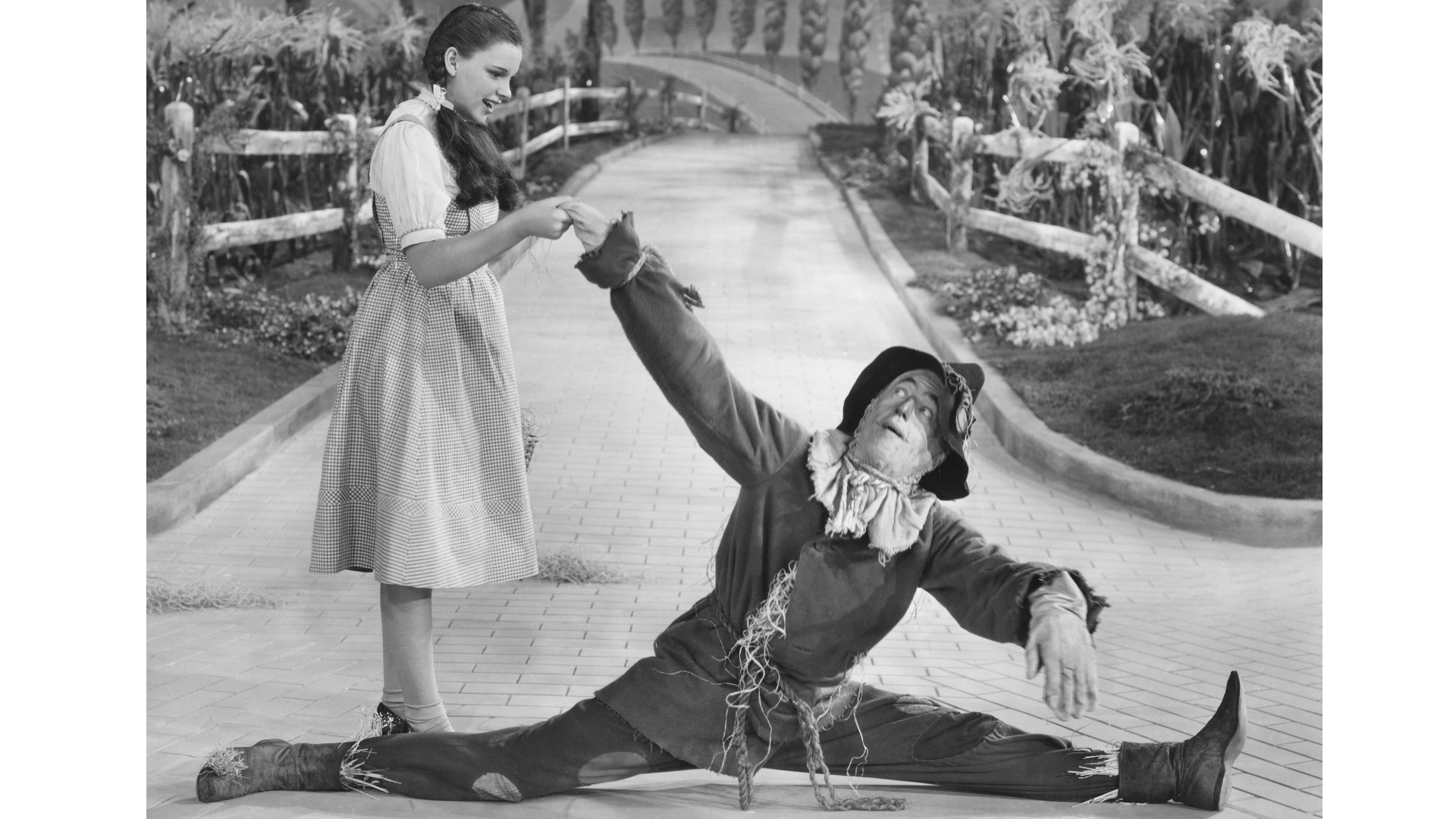 Black-and-white image of the Scarecrow doing the splits in Wizard of Oz