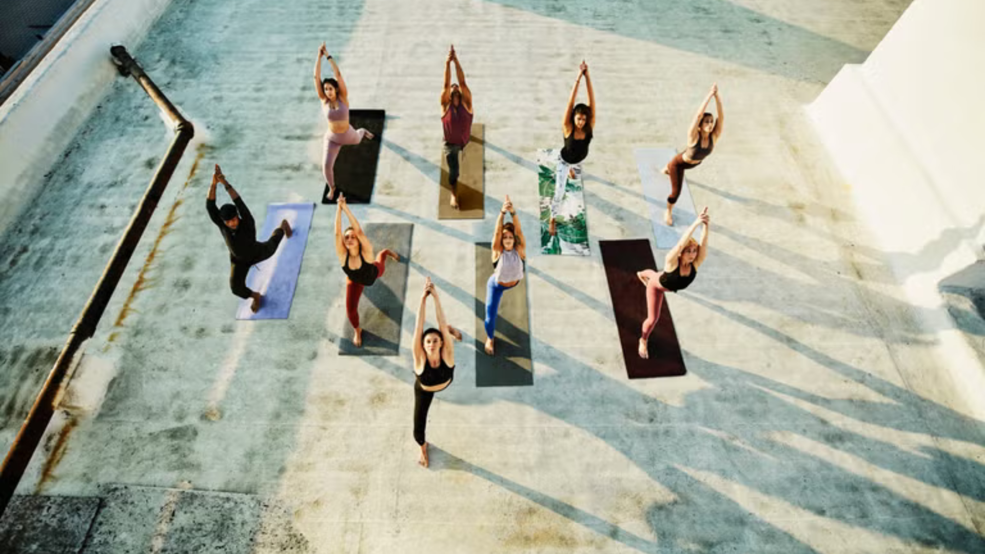 Group yoga class practicing outside on a rooftop with the late-afternoon sun in the background